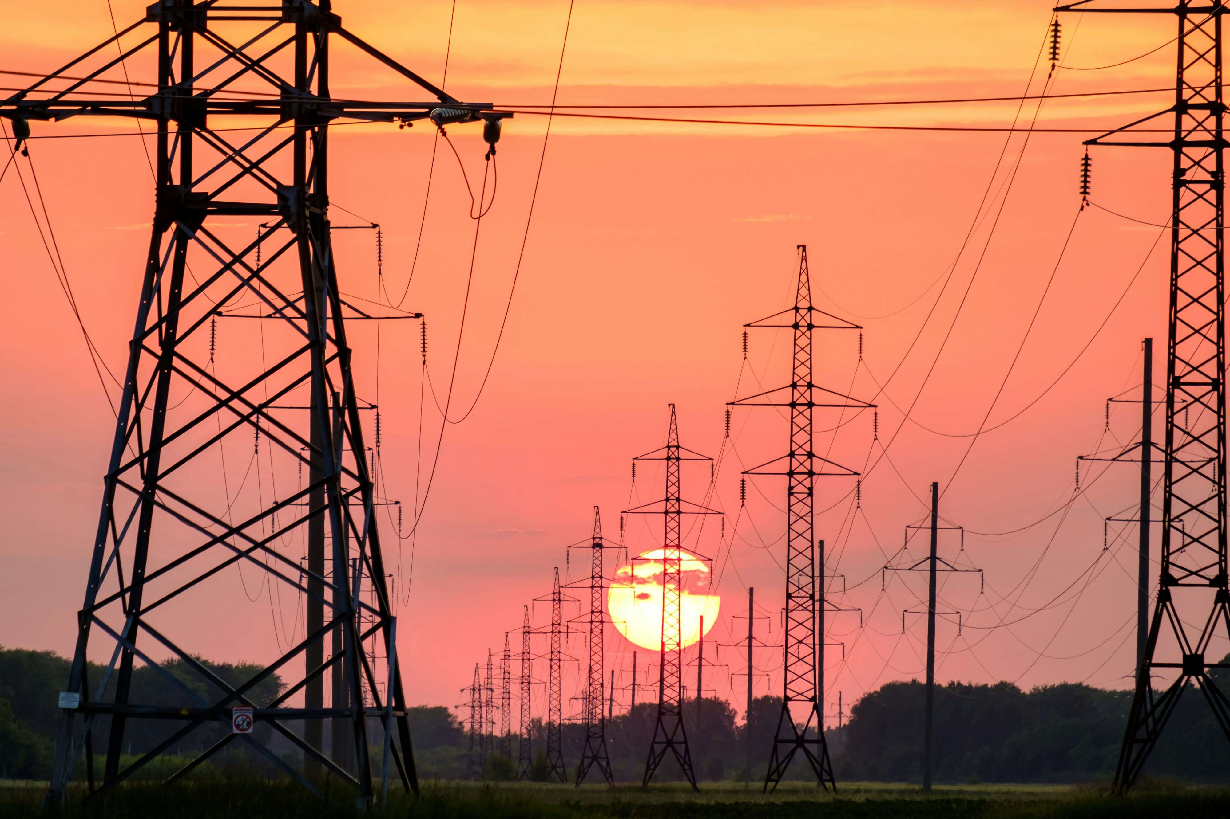 High-voltage transmission towers and power lines stretch across a field.